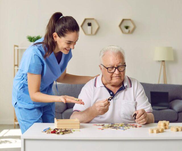nurse helps elderly man solve a jigsaw puzzle